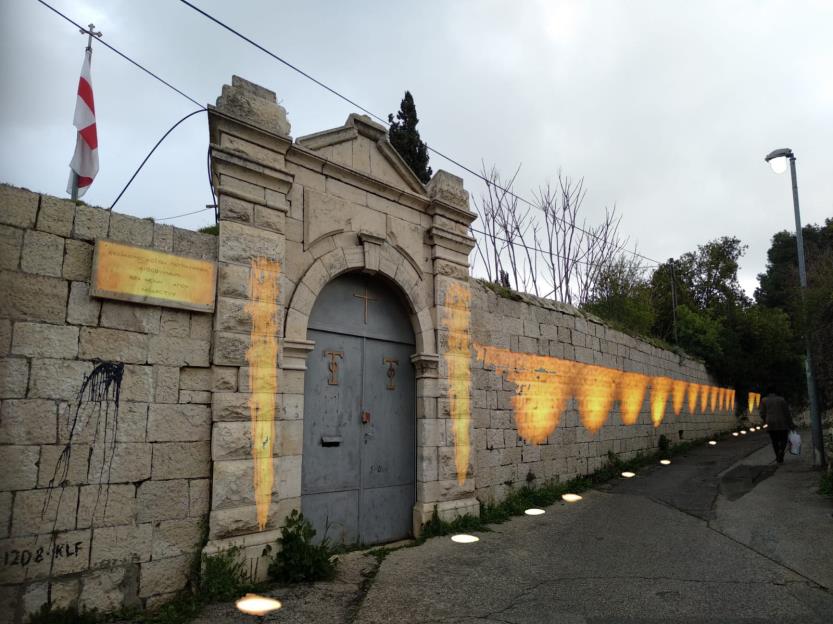 The proposal: the same wall washed with warm light from below, pools of it running down the lane past the gate.
